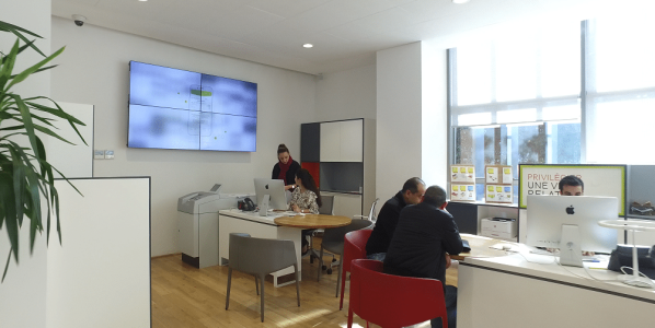 Photo d'un mur écran dans un open space pour la publication des nouveautés de l'entreprise.